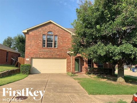 a brick house with a garage door and a tree